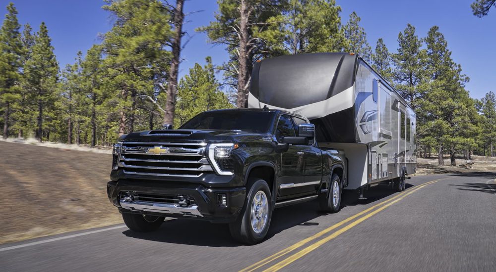 A popular Chevy Silverado for sale, a black 2025 Chevy Silverado 2500 HD High Country, is towing a camper.