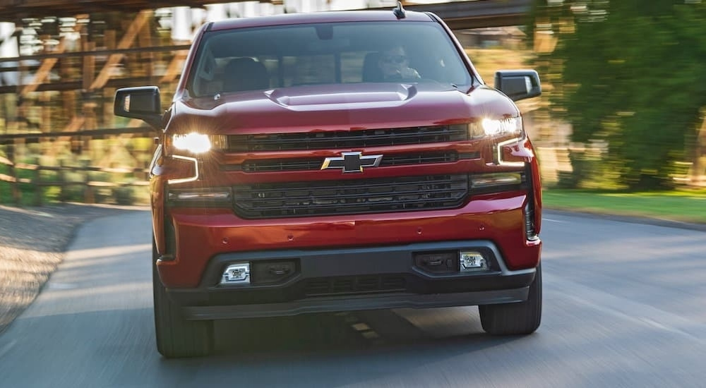 A red 2020 Chevy Silverado 1500 is driving on a winding road.
