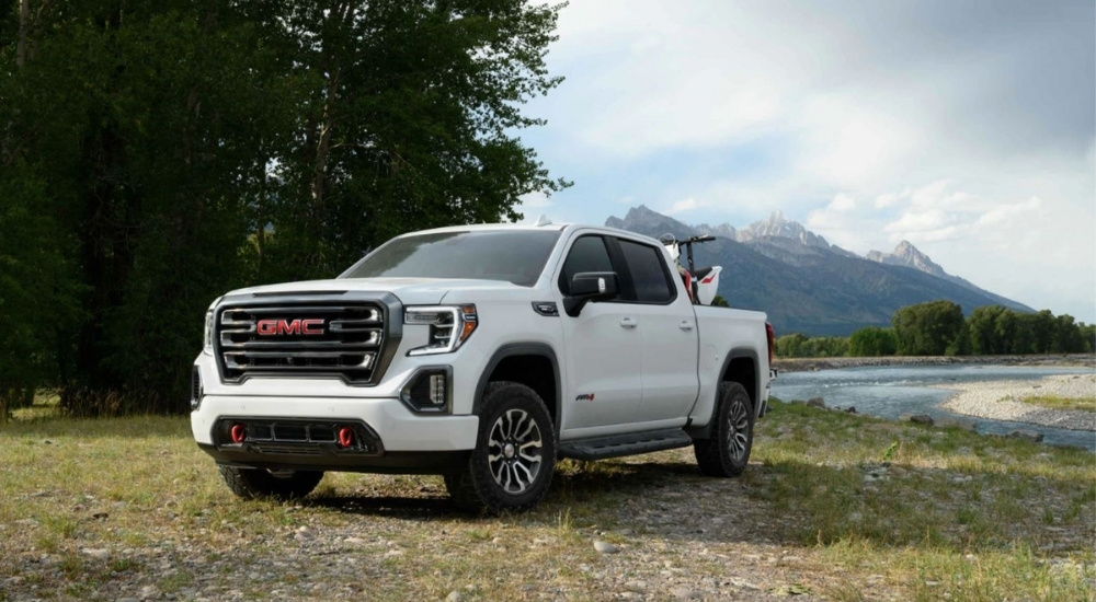 A white 2021 GMC Sierra 1500 AT4 is parked near a riverbed after leaving a used GMC dealer.