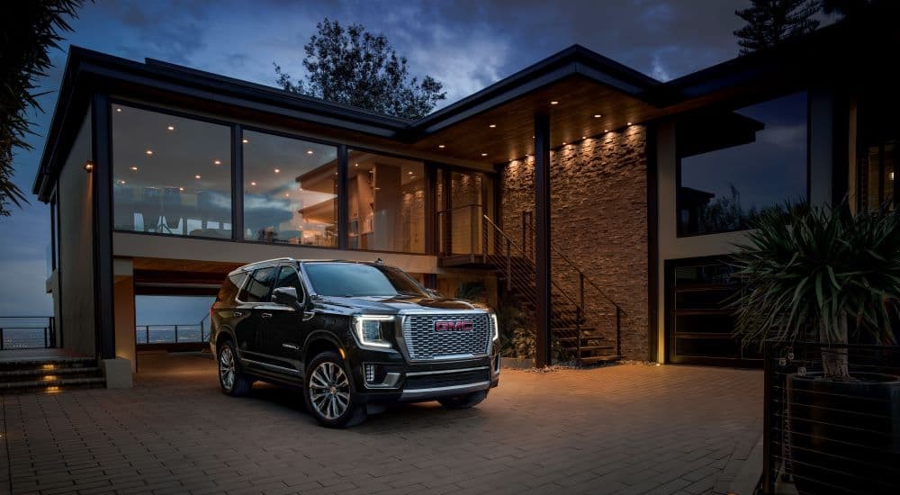 A black 2023 GMC Yukon Denali is parked in a driveway after leaving a used GMC dealer.