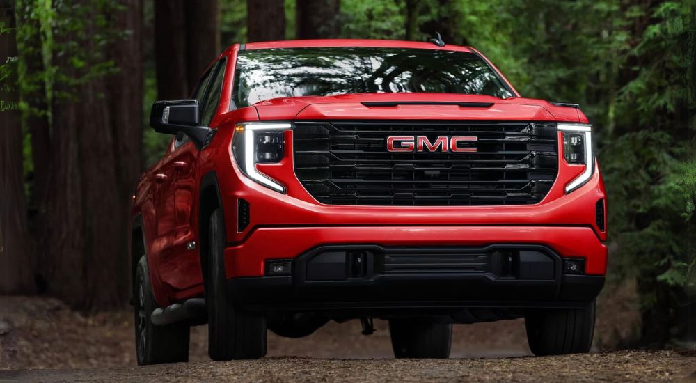 A red 2025 GMC Sierra 1500 for sale driving on a trail.