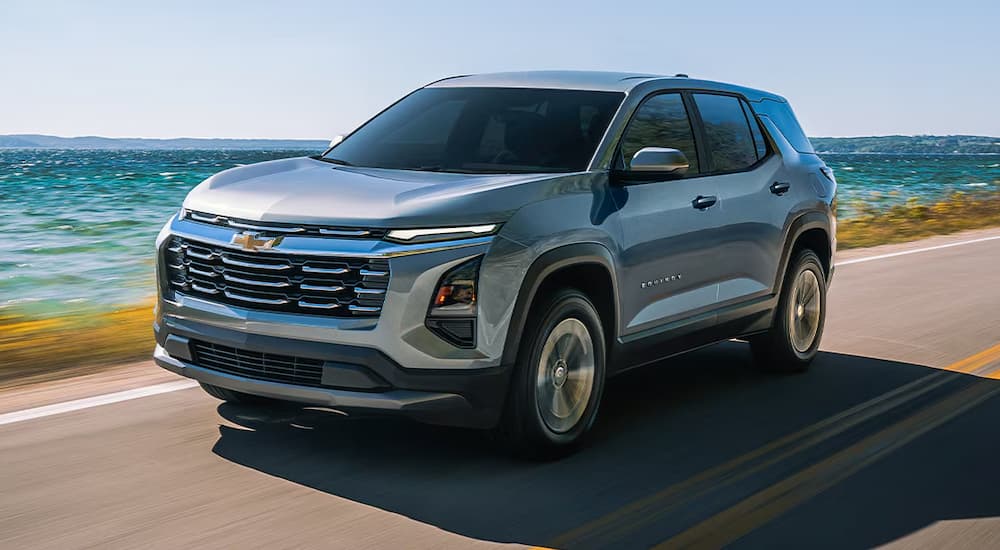 Grey 2026 Chevy Equinox driving on a road next to the ocean.