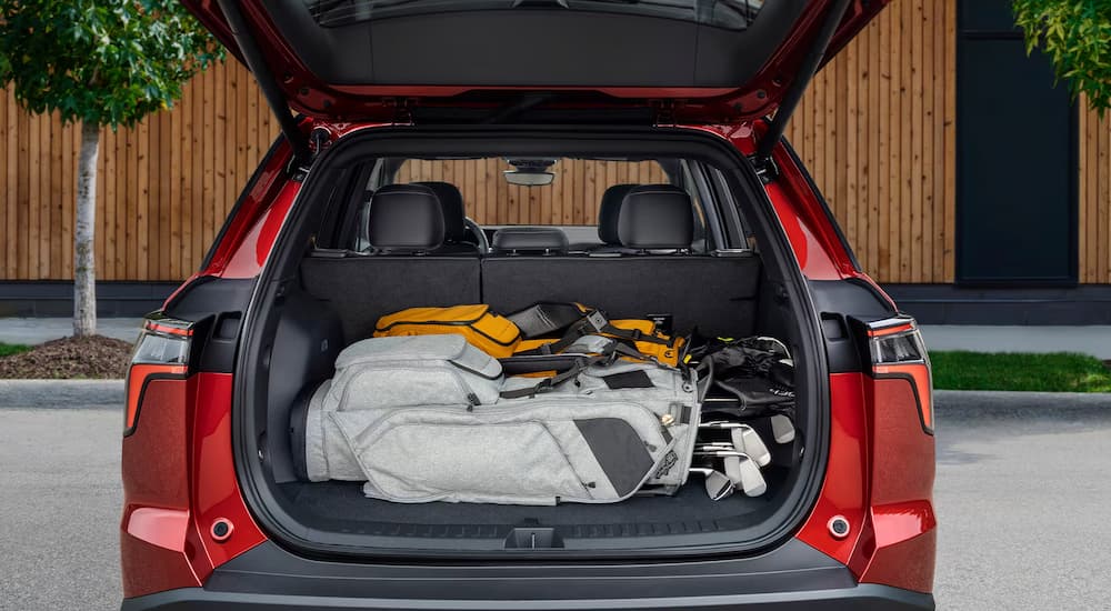 Golf gear and bags in the back of a red 2026 Chevy Equinox.