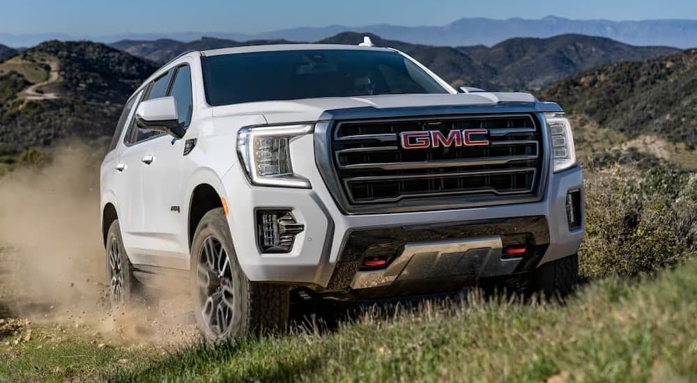 A white 2023 GMC Yukon AT4 driving offroad.