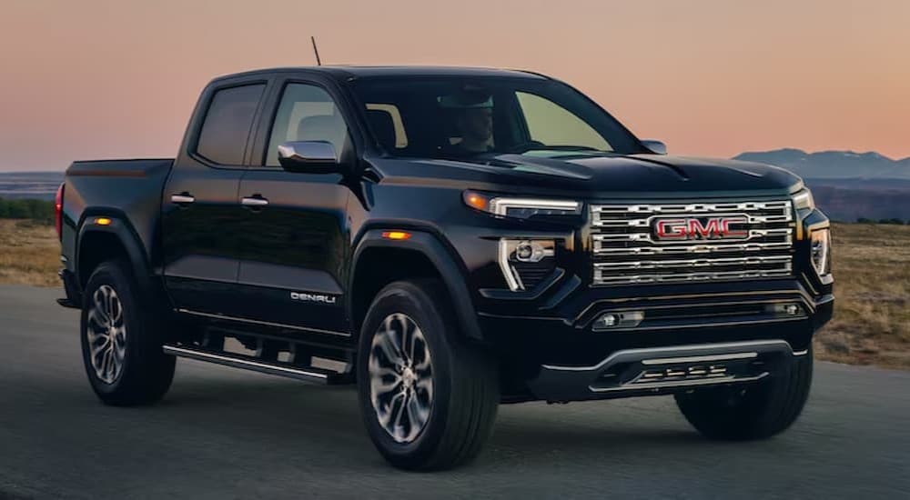 A black 2024 GMC Canyon parked near a used GMC for sale.