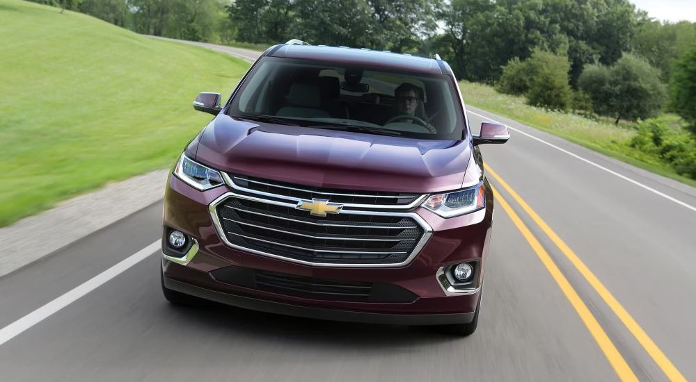 Top of a dark red 2018 Chevy Traverse driving down a road.