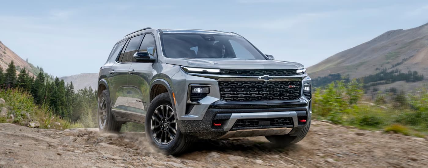 Silver 2025 Chevy Traverse driving off-road on a hill.