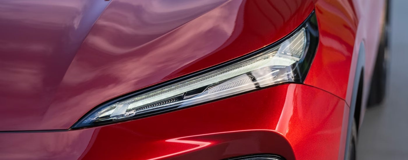 A close up of the front headlight on a red 2024 Buick Envision.