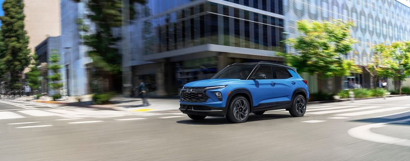 A blue 2024 Chevy Trailblazer RS is shown driving on a city street.