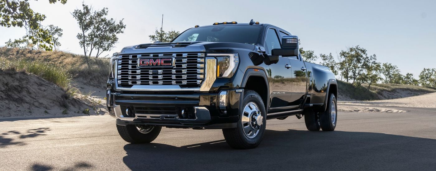 A black 2024 GMC Sierra 3500HD Denali is driving on an open road.