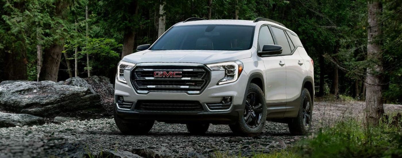 A white 2024 GMC Terrain AT4 is shown parked off-road after leaving a GMC dealer.