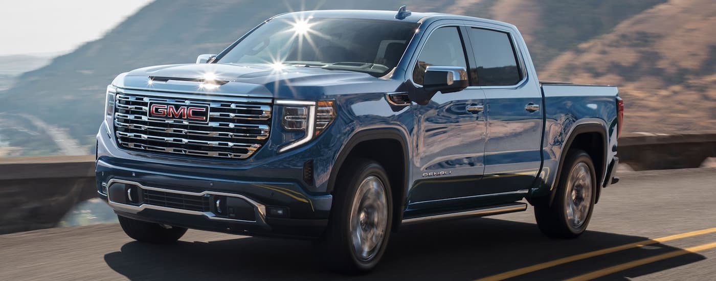 Blue 2026 GMC Sierra 1500 driving down a road.