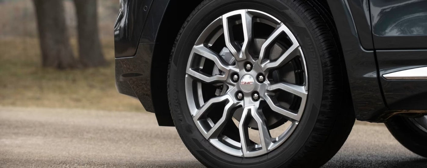 A close up of the tire and silver rim on a black 2022 GMC Terrain.
