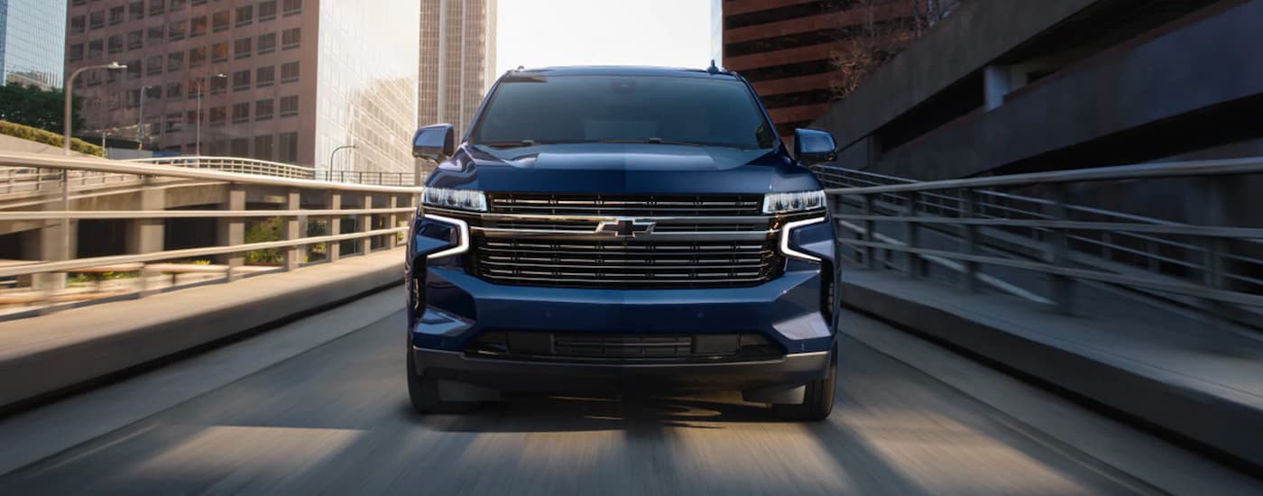Front of a blue 2023 Chevy Tahoe driving over a bridge.