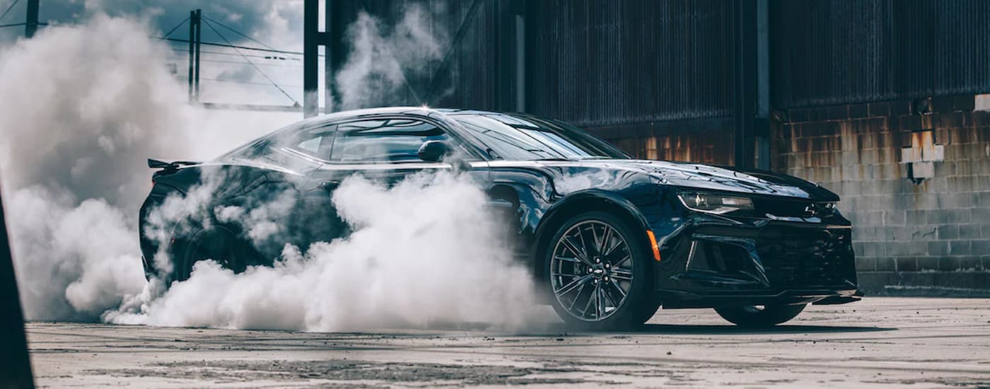 Side of a black 2022 Chevy Camaro performing a burnout.